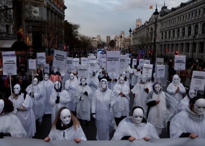 Women wearing masks hold signs with the names of those who, according to them, are victims of gender-based violence, during a demonstration to mark International Women's Day in Madrid, Spain, March 8, 2025. REUTERS/Susana Vera