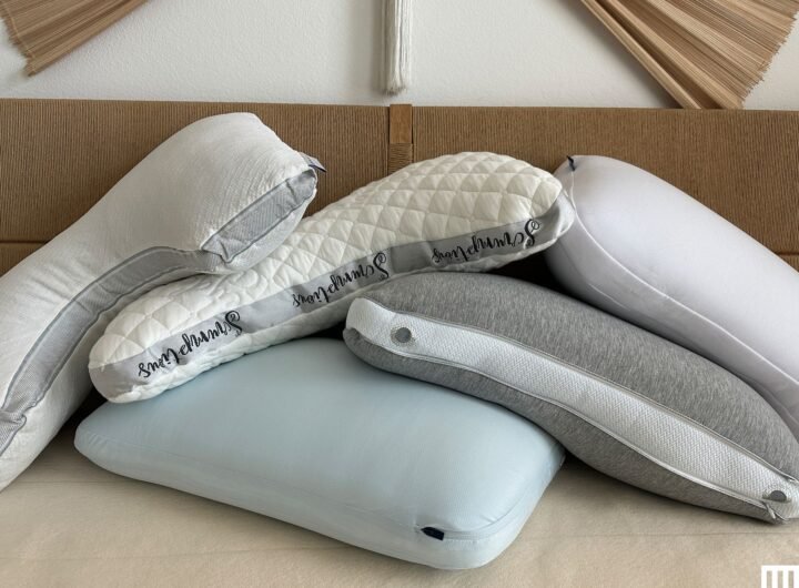 Stack of different shaped bed pillows on top of a beige mattress with a woven bed headboard behind them