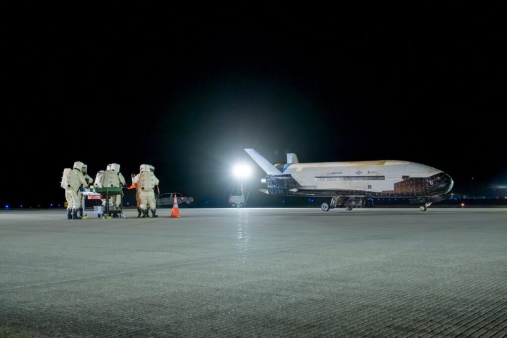 Technicians standing near the recently landed X-37B spaceplane.